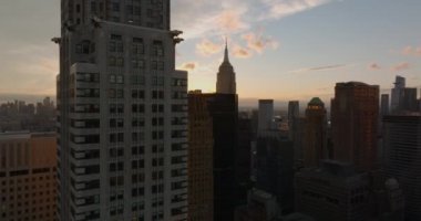 İleri, kasabanın üstünden uçar. Şehir manzarası, batan güneşe karşı görkemli Empire State Binası. Manhattan, New York City, ABD
