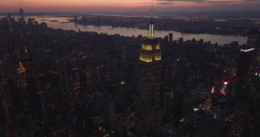Akşam şehrinin üzerinden uç. Sarı ışık ikonik Empire State Binası 'nın tepesinde. Akşam karanlığında şehir manzarası. Manhattan, New York City, ABD