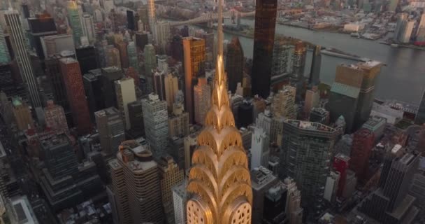 Leť nad ozdobnou korunou a vysokou věží na vrcholu budovy Chrysler osvětlenou zlatým západem slunce. Manhattan, New York City, USA — Stock video