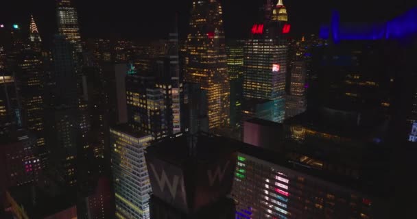 Forwards fly between high rise buildings in city centre. Tilt down on Times square with flashing advertisements. Night in downtown. Manhattan, New York City, USA — Vídeo de Stock