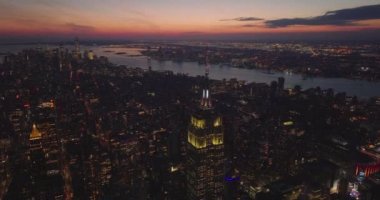 Alacakaranlıktaki büyük şehrin havadan panoramik görüntüsü. Empire State Binası 'nın tepesindeki ışıklı süslemeye doğru eğil. Manhattan, New York City, ABD