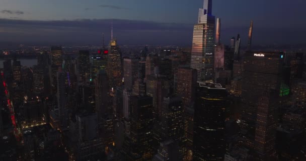 İleriye doğru yükselen hava kararınca şehrin üzerinde uçar. Modern parlak gökdelenler renkli alacakaranlık gökyüzünü yansıtıyor. Manhattan, New York City, ABD — Stok video