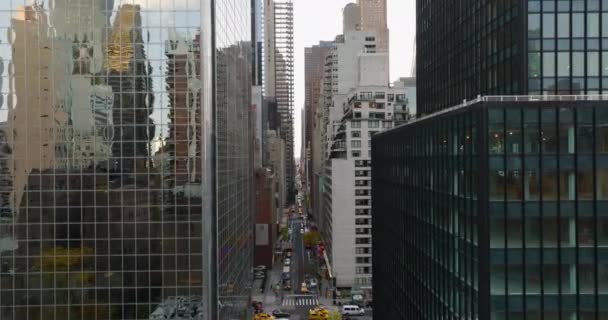 Forwards fly above street in city. Road lined by tall office or apartment buildings. Glossy glass facade reflecting surroundings. Manhattan, New York City, USA — Vídeo de Stock