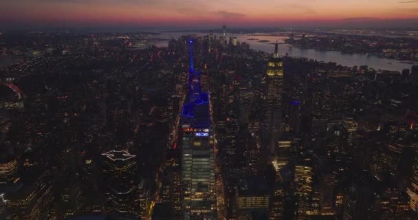 Avante voe acima da cidade ao entardecer. Iluminados topos coloridos de arranha-céus. Blue One Vanderbilt e Empire State Building amarelo. Manhattan, Nova Iorque, EUA — Vídeo de Stock