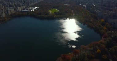 Central Park 'ın sonbaharında parlayan su yüzeyinin havadan görünüşü. Modern iş gökdelenlerini gözler önüne serin. Manhattan, New York City, ABD