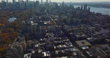 İleri, Central Park yakınlarındaki yerleşim yerlerindeki binaların üzerinden uçuyor. Gökdelenleri olan bir gökyüzü. Manhattan, New York City, ABD