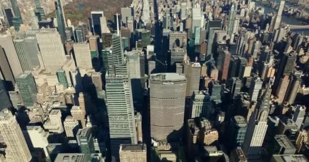 High angle view of tall skyscrapers in midtown lit by bright sun. Tilt up reveal of cityscape with rivers and large Central Park. Manhattan, New York City, USA — стоковое видео