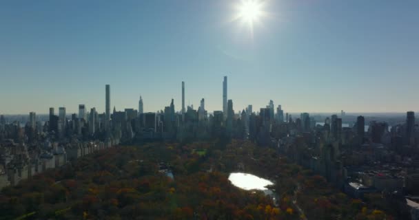 Imágenes panorámicas de Central Park y rascacielos del centro contra el sol. Vista retroiluminada de otoño. Manhattan, Nueva York, Estados Unidos — Vídeos de Stock