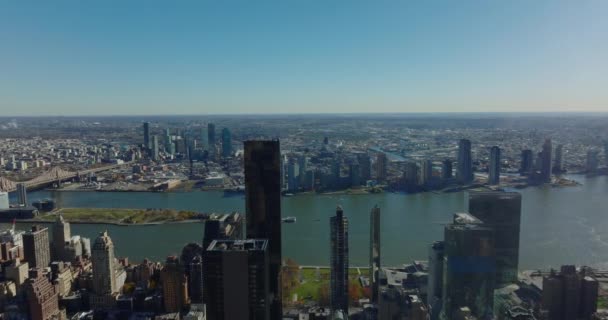 East River rıhtımındaki yüksek binaların ve karşı kıyıdaki Queens bölgesinin havadan panoramik görüntüsü. Güneşli bir günde gökyüzü açık. Manhattan, New York City, ABD — Stok video