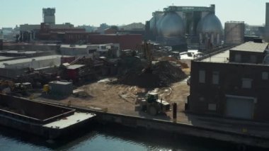 Slide and pan aerial shot of truck arriving on loose material dump. Loading material on barge. New York City, USA