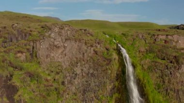 Kayanın tepesinden uç. Su, Seljalandsfoss şelalesinin derinliklerine düşüyor. Kuzey manzarasını korumuş. İzlanda