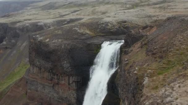 Слайд и панорамный снимок воды, катящейся по краю скалы и падающей вдоль скалы. Удивительная северная природа. Хайффельд, Исландия — стоковое видео