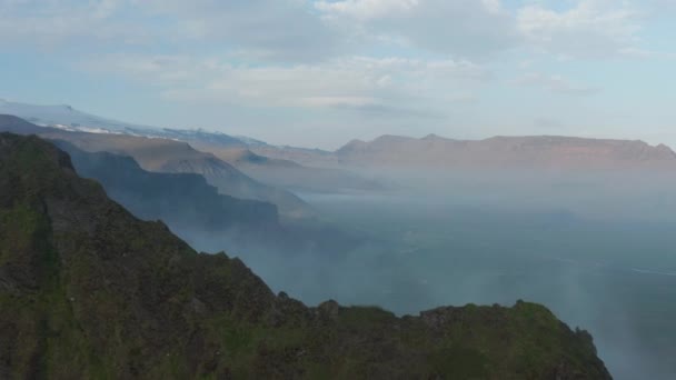 Vue panoramique aérienne à couper le souffle sur le paysage nordique. Grande vallée verte inondée de brume et de crêtes montagneuses. Islande — Video