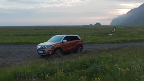 Slide i pan strzał popularnego SUV rodzinnego samochodu stojącego na poboczu brudnej drogi. Piękna przyroda o wschodzie lub zachodzie słońca w tle. Islandia — Wideo stockowe