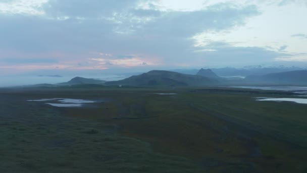 Pagi panorama cuplikan lanskap Nordic. Padang rumput hijau datar luas dengan permukaan air dan pegunungan di latar belakang. Lembah dibanjiri kabut. Islandia — Stok Video