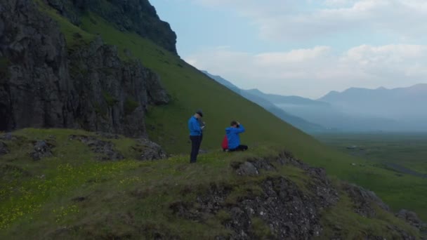 Diapositiva y panorámica de grupo de personas que fotografian increíble panorama del paisaje. Amplio valle verde bordeado de empinada pendiente. Islandia — Vídeo de stock