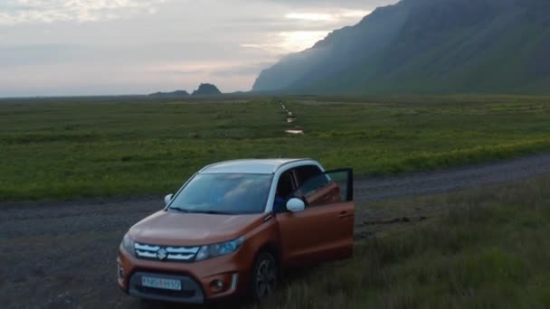 비포장 도로에서 서 있는 최신 SUV 차량 위로 날아. 전진하는 개미들은 목장의 잔잔 한 시내 위로 곧게 날아간다. 산등성이 뒤에 요. 아이슬란드 — 비디오