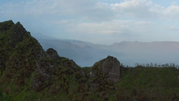 Achterwaarts onthullen van grillige rotsachtige bergrug gekweekt met gras. Mistige valleien en hoge bergen op de achtergrond. IJsland — Stockvideo
