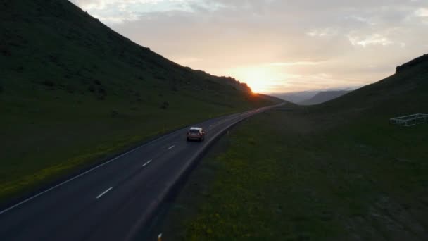 夕阳西下时，越野车在路旁行驶。傍晚时分,天空五彩斑斓.在保存完好的北欧自然中继续追踪车辆。冰岛 — 图库视频影像