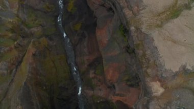 Yüksek açılı şelale manzaralı. Akıntı kayanın kenarından derin vadiye doğru akıyor. Yukarı kaldır ve volkanik manzara manzarasını göster. Haifoss, İzlanda