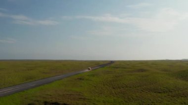 Düz arazinin üzerinde uç. Golden Hour 'da Kuzey Avrupa kırsalından geçen bir SUV arabası. İzlanda