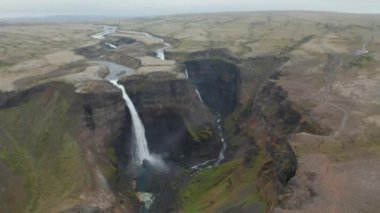 Yüksek açılı şelaleli kayalık vadi manzarası. Akan su akıntıları derin kanyona dökülüyor. Doğal turist eğlencesi. Haifoss, İzlanda
