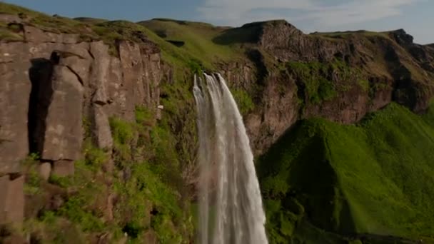 Обильный поток воды, падающей вдоль скалы в глубины. Летать над красивыми пейзажами. Исландия — стоковое видео