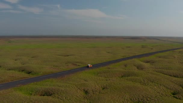 Imágenes aéreas de coches conduciendo por carretera en paisaje plano. Viaje por carretera a través de vastos pastizales de naturaleza nórdica. Islandia — Vídeo de stock