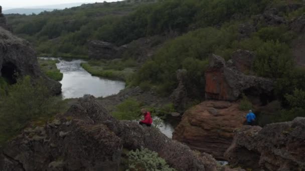 Mladý milovník přírody kráčí po skalnatém výběžku nad kaňonem s potokem. Severská sopečná krajina. Island — Stock video