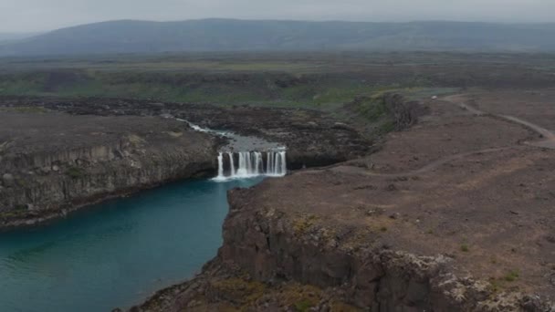 Slide e pan tiro de cachoeira no riacho. Lagoa profunda com água azul abaixo da cascata. Paisagem vulcânica incrível. Aldeyjarfoss, Islândia — Vídeo de Stock