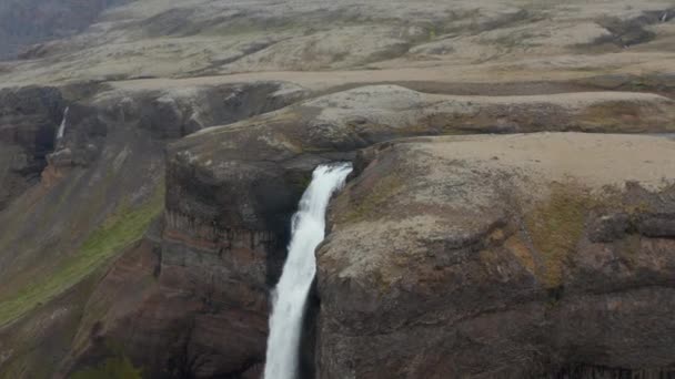 Repülj át a szikla szélén. Felfedi a magas vízesést. A fehér víz tömege mélyre zuhan. Csodálatos megőrzött skandináv természet. Haifoss, Izland — Stock videók