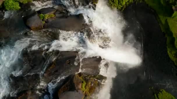 Aerial birds eye overhead top down ascending footage of water stream falling into depth. Picturesque green nature lit by setting sun. Seljalandsfoss waterfall, Iceland — Stock Video
