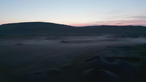 Romantiskt landskap i skymningen. Ojämn terräng i dalen höljd i dimma och färgglad skymning himmel. Island — Stockvideo