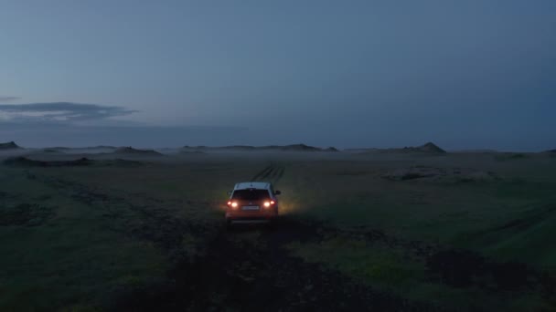 Coche invirtiendo en camino de hierba fuera de la carretera al anochecer. Aventureros vagando en un paisaje nórdico desconocido. Islandia — Vídeos de Stock