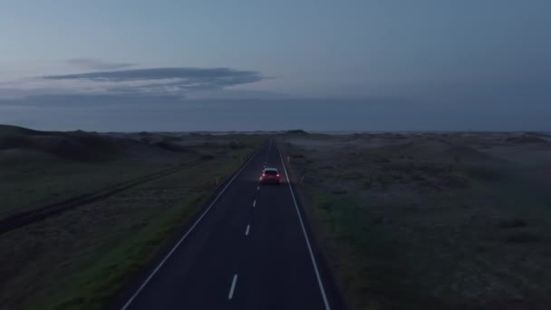 Voorwaarts volgen van auto bewegen op de weg in kale vlakke landschap. Road trip op het Noordse platteland in de schemering. IJsland — Stockvideo