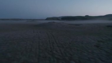 Vadideki düz arazinin üzerinde alçak uçuş. Gün batımından sonra yer üstü sisli. SUV arabasındaki insanları açığa çıkarmak. İzlanda