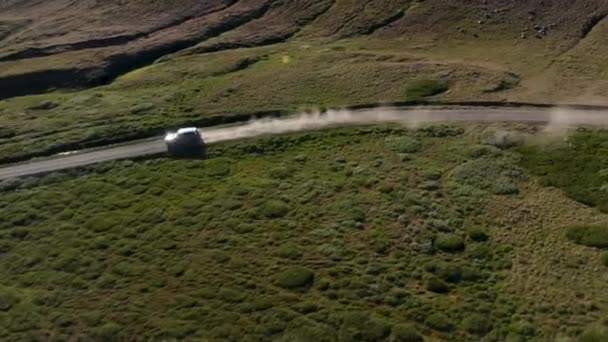 Hög vinkel syn på SUV bil rör sig på dammiga vägen mellan grön vegetation på landsbygden. Vulkaniska landskap. Island — Stockvideo