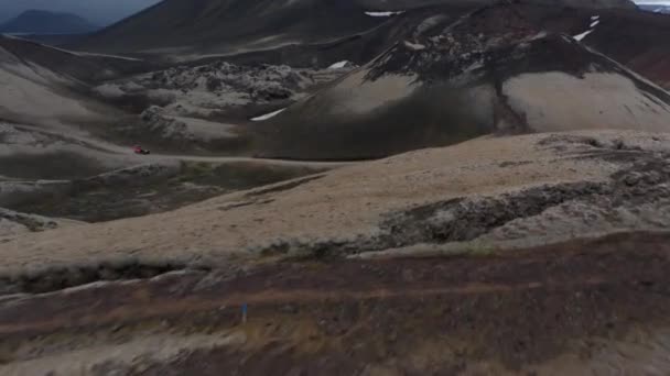 Χαμηλή πτήση πάνω από ηφαιστειακό έδαφος. Αποκαλύπτοντας το χιόνι και το αυτοκίνητο οδήγηση σε χωματόδρομο στην κοιλάδα. Ισλανδία — Αρχείο Βίντεο