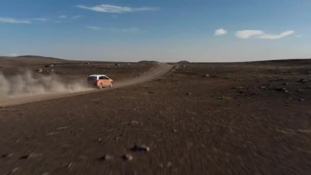 Voiture se déplaçant sur la route de terre menant à travers la plaine volcanique stérile. Vent soufflant des nuages de poussière soulevée. Islande — Video