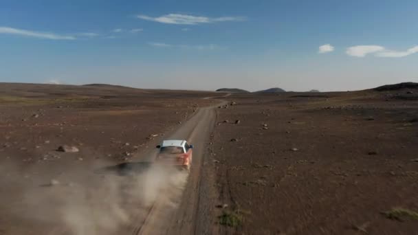 Framåt flyger över vulkanisk ödemark. SUV bil stiger damm från grusväg i nordisk landsbygd. Island — Stockvideo