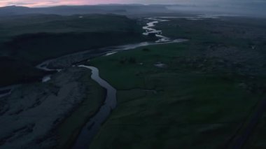 Manzarada akan nehrin yüksek açılı görüntüsü. Akşam manzarasını renkli alacakaranlık gökyüzü ile yukarı eğ. İzlanda