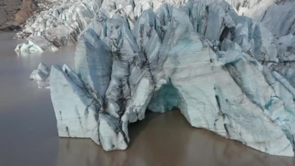 Slide and pan aerial shot of ice blocks on front of glacier standing in water. Arctic nature scenery. Iceland — Stock Video