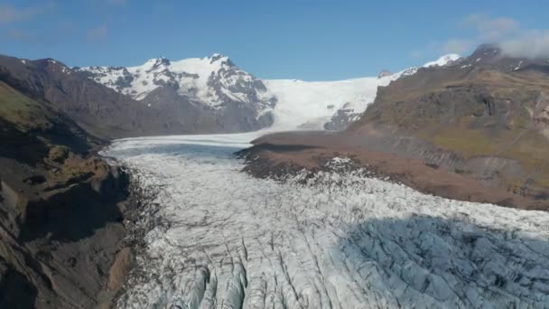 Imagens aéreas panorâmicas descendentes de grande fluxo de gelo no vale da montanha. Dia ensolarado na paisagem nórdica. Islândia — Vídeo de Stock