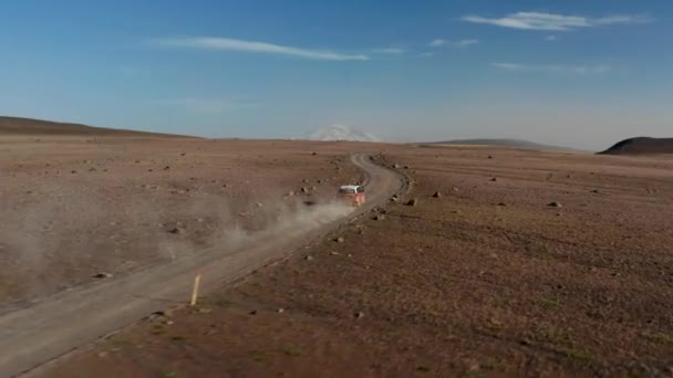 Kırsalda gezen bir SUV arabası ve yükselen toz. Çorak ovalar ve uzak dağlar. Güneşli bir gün. İzlanda — Stok video