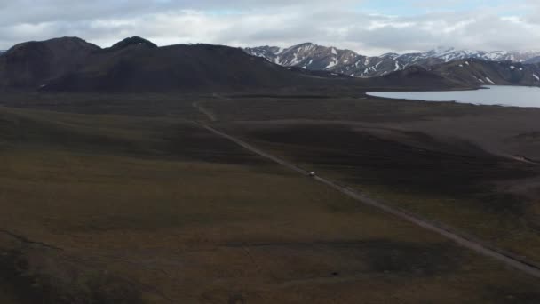 Aerial panoramische beelden van het voertuig rijden door prachtige Scandinavische landschap met besneeuwde bergen in de verte. IJsland — Stockvideo