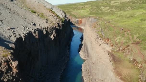 Riprese ascendenti di burrone roccioso con banchi di colonne di basalto. Persone che camminano su sentieri paralleli. Studlagil Canyon, Islanda — Video Stock