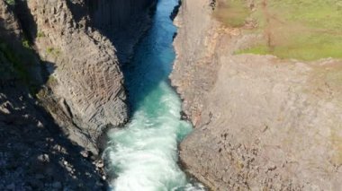 Kaya duvarları olan dar bir geçitte akan akıntının havadan inen görüntüsü. Çeşit çeşit bazalt sütunlarla çevrili bir dere. Studlagil Kanyonu, İzlanda