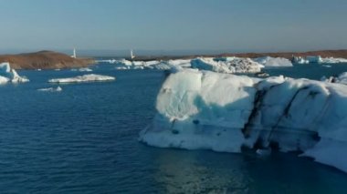 Yüzen buz bloklarıyla gölün üzerinde uçuyorlar. Buzuldaki kırıntılar. Güneşli bir günde İskandinav manzarası. İzlanda