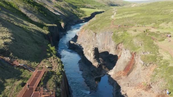 空中俯冲的自然吸引镜头.水流在岩石峡谷中流动.人们崇拜独特的柱状玄武岩结构.Studlagil Canyon，冰岛 — 图库视频影像