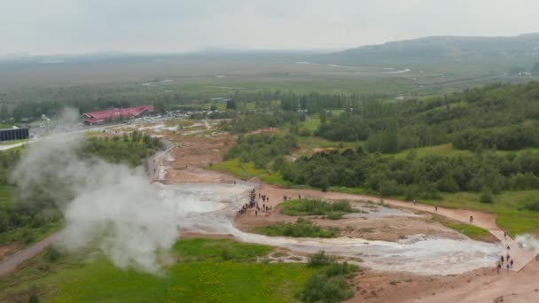Lidé stojí a dívají se, jak gejzír vybuchuje vařící vodou. Snímek a pánev geotermální aktivity v přírodě. Island — Stock video
